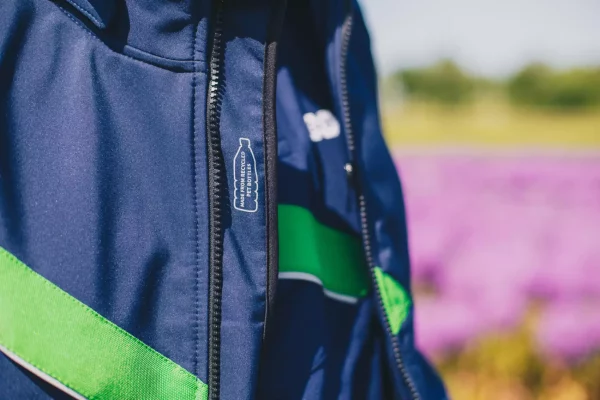 Detail van een werkjas van AB Vakwerk met groene accenten