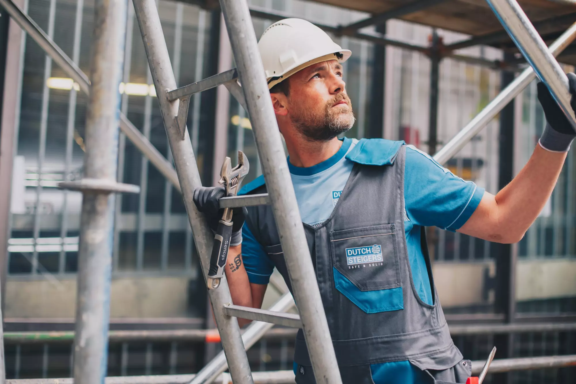 Steigerbouwer met helm in werkkleding van Dutch Steigers aan het werk op de steiger