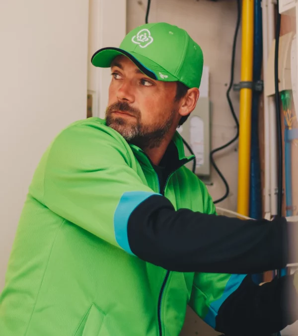 KPN-monteur met pet in groene werkkleding aan het werk