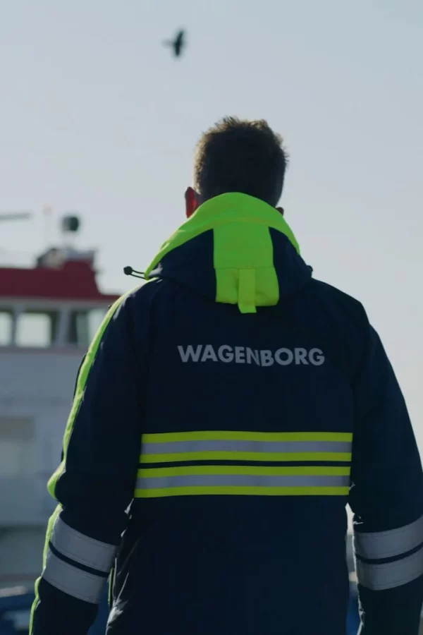 Wagenborg-medewerker in werkjas met reflectie, van achteren gezien