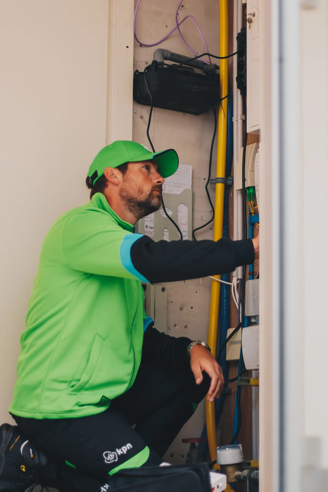 KPN-monteur in groene werkkleding bij een meterkast