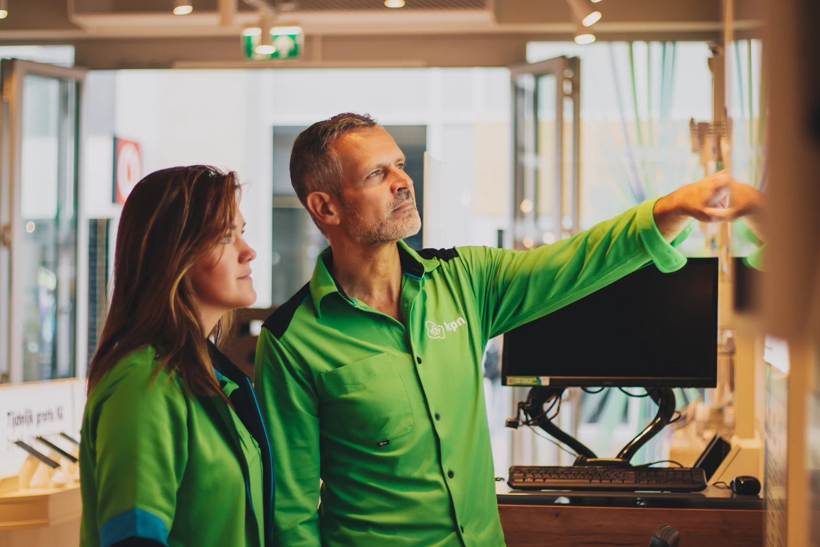 KPN-medewerkers in groene bedrijfskleding in de winkel