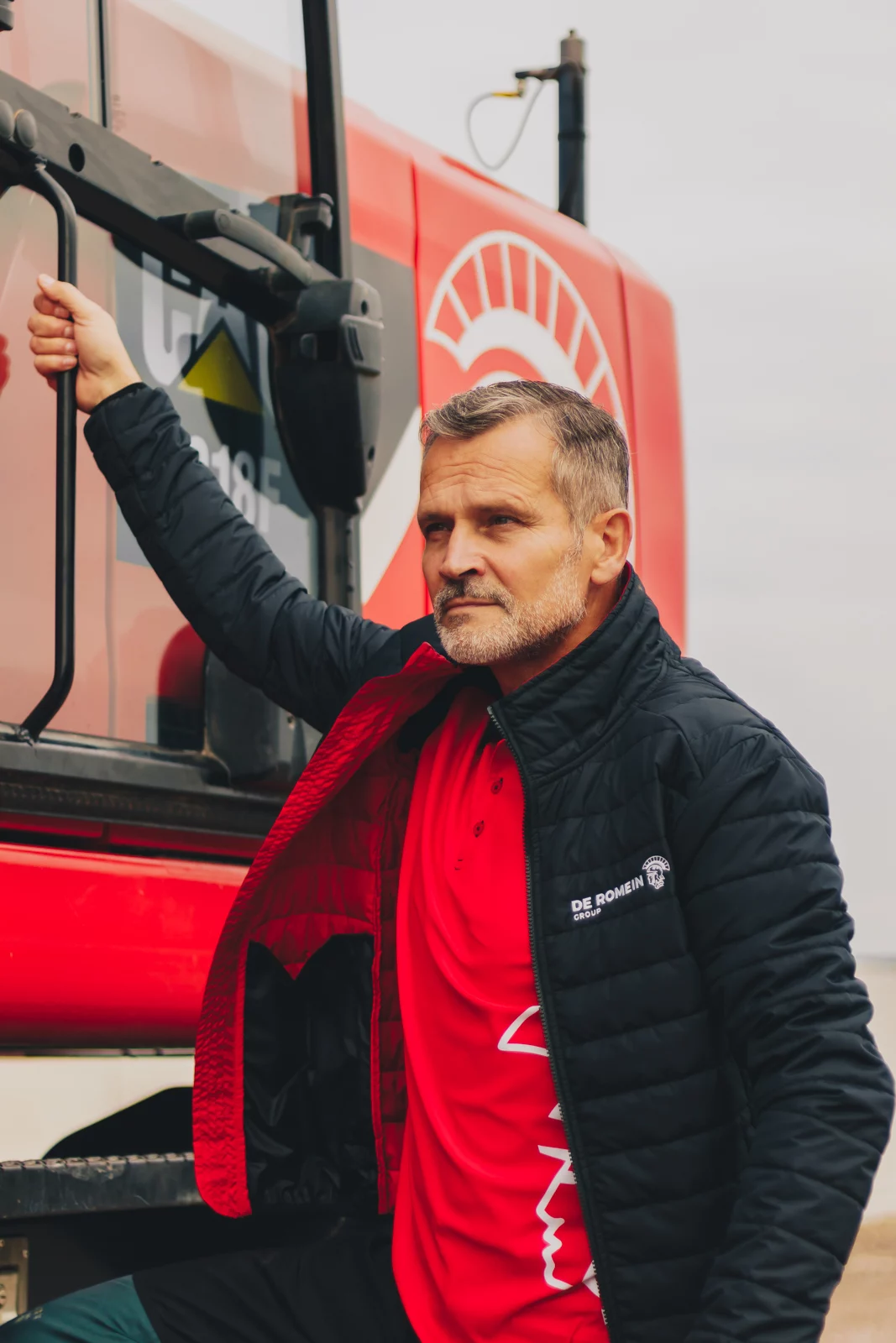 Medewerker van De Romein in rode werkjas bij een machine