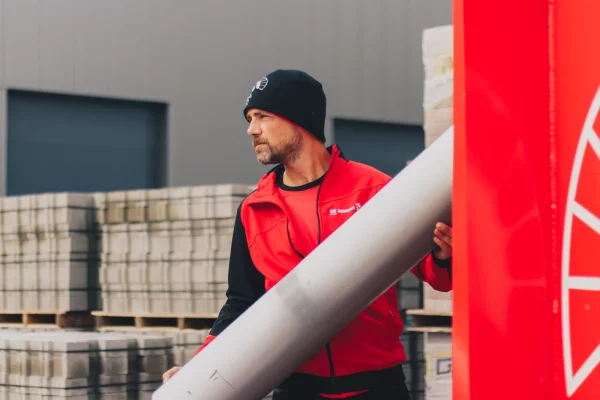 Medewerker van De Romein in rode bodywarmer tussen de stenen