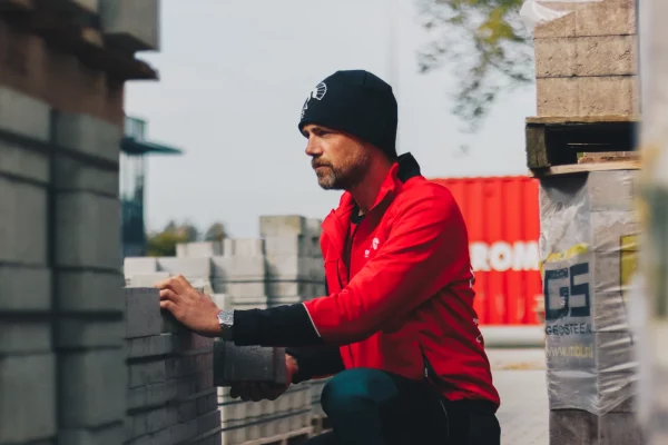 Medewerker van De Romein in rode werkjas aan het werk
