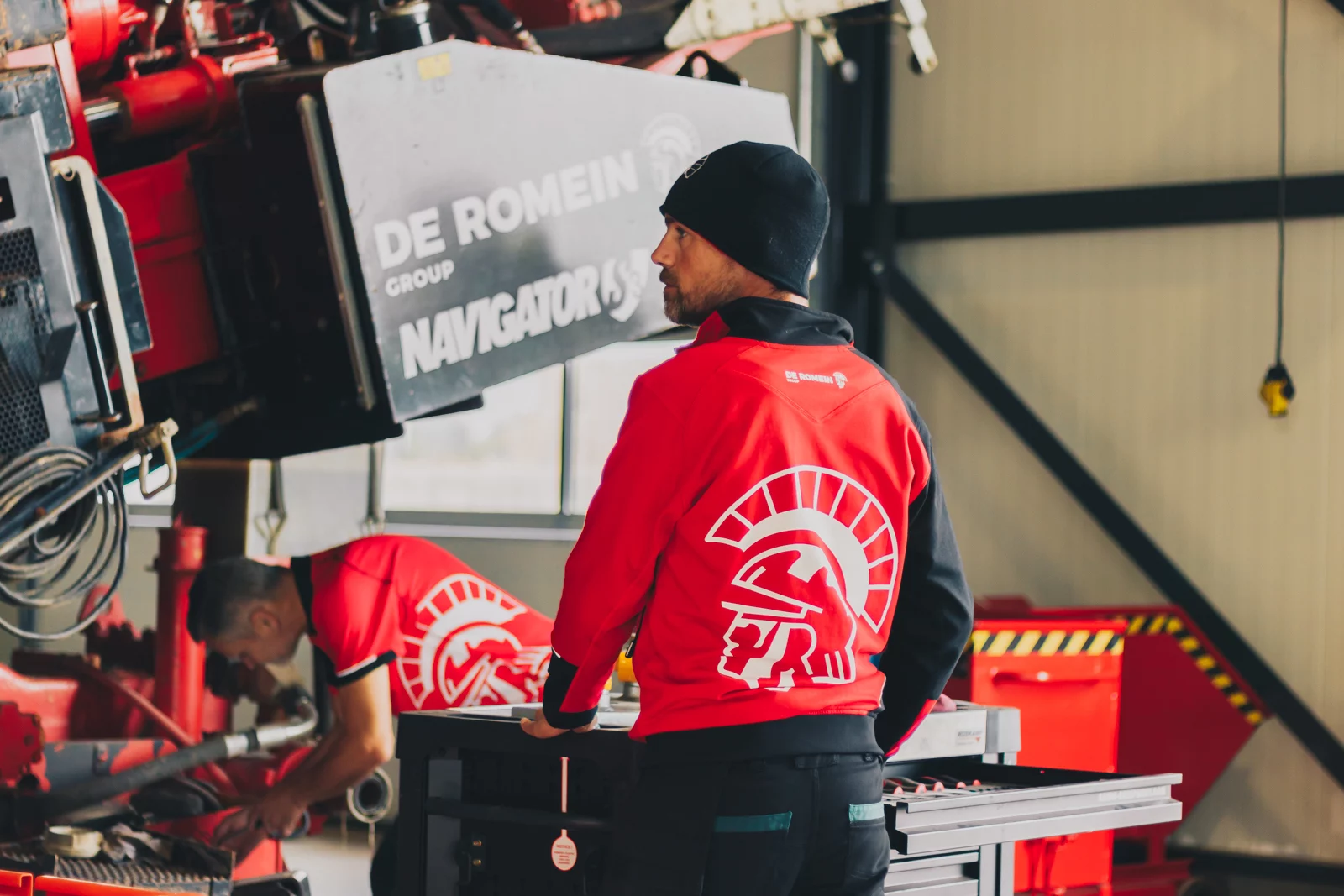 Medewerkers van De Romein in rode werkkleding in de werkplaats