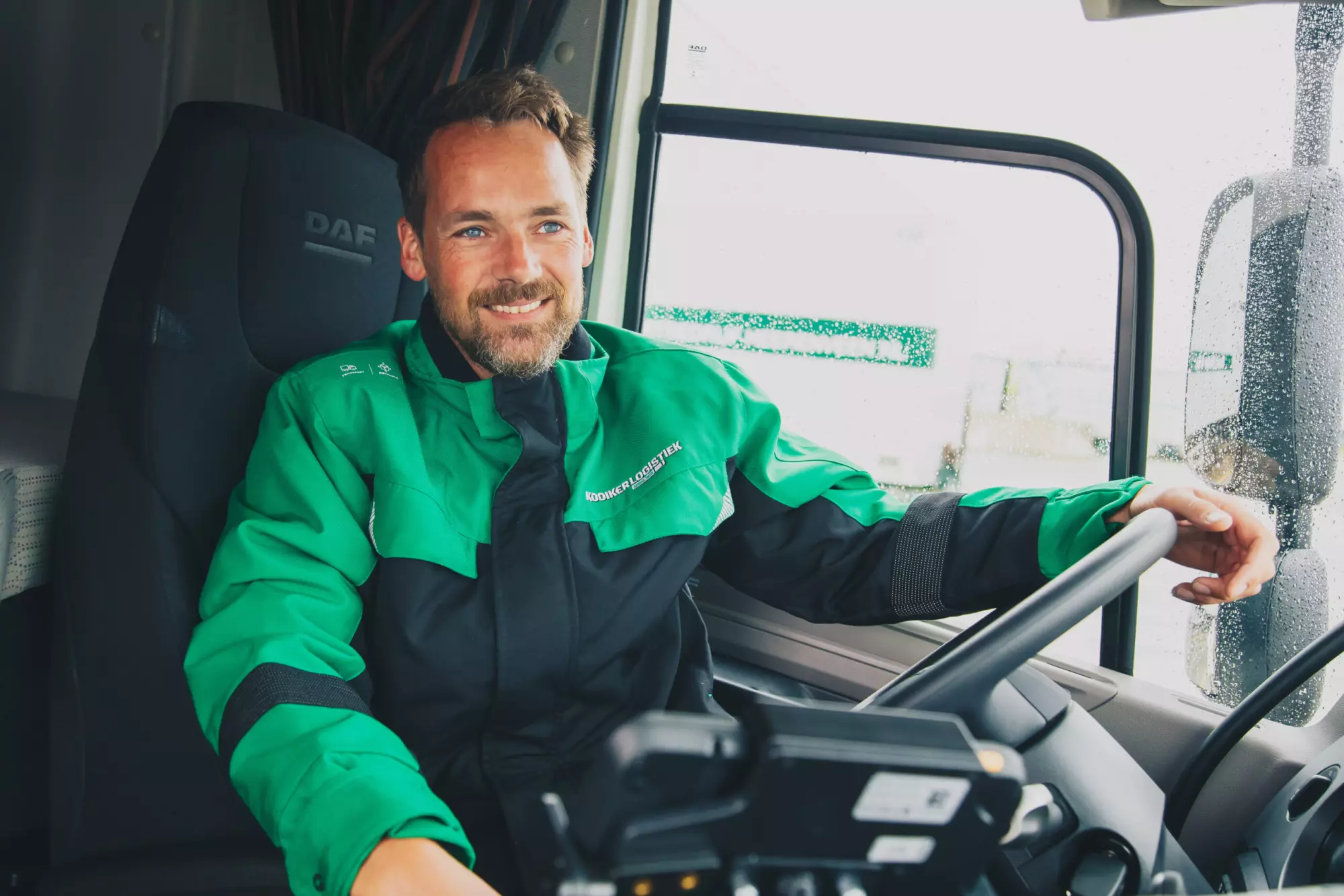 Chauffeur van Kooiker Logistiek in groene werkjas achter het stuur