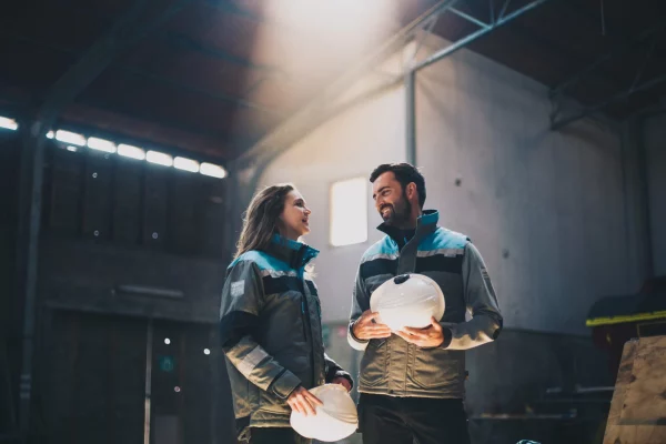 Twee medewerkers met helm in werkkleding in een magazijn