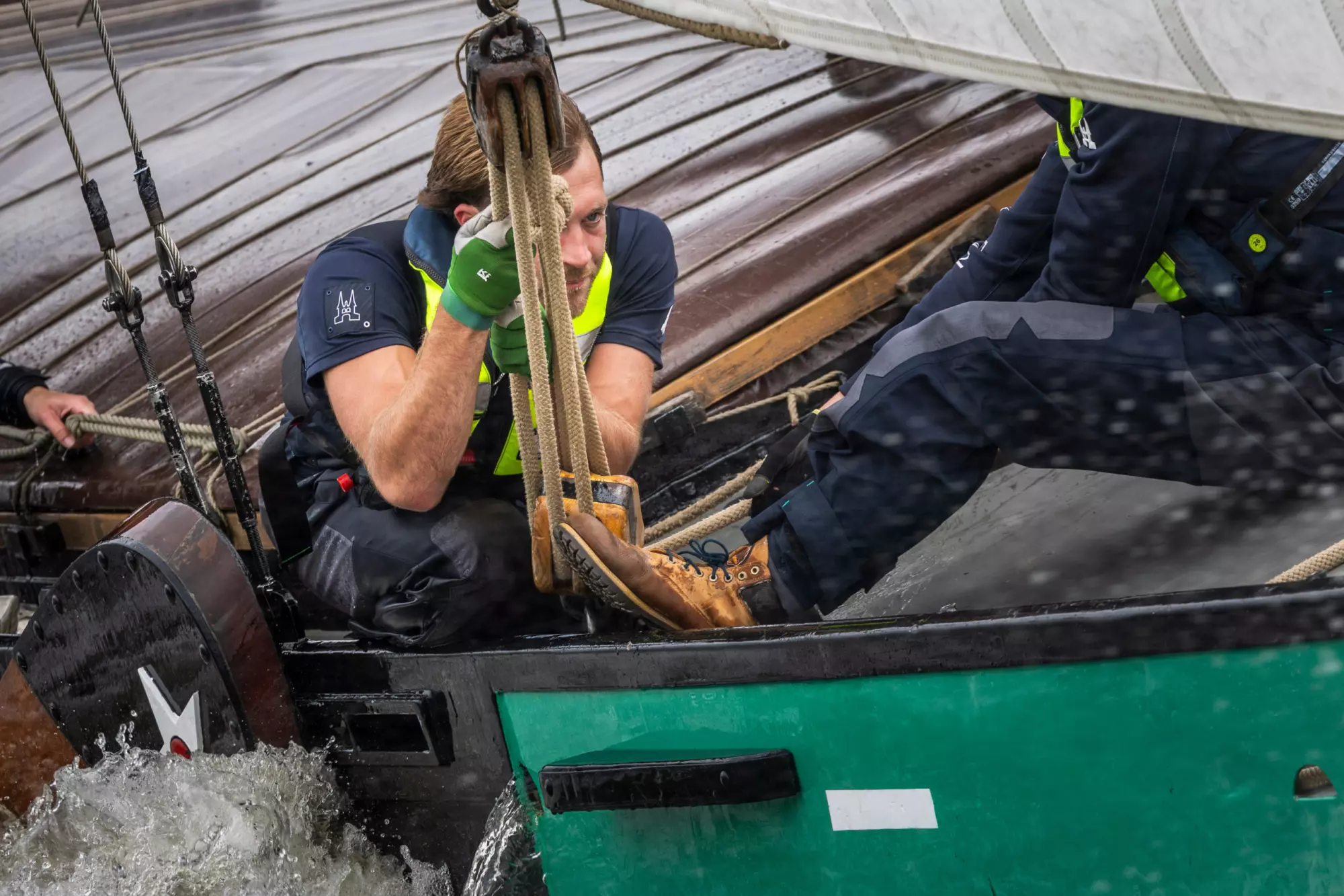 Bemanningslid van De Sneker Pan trekt aan een lijn