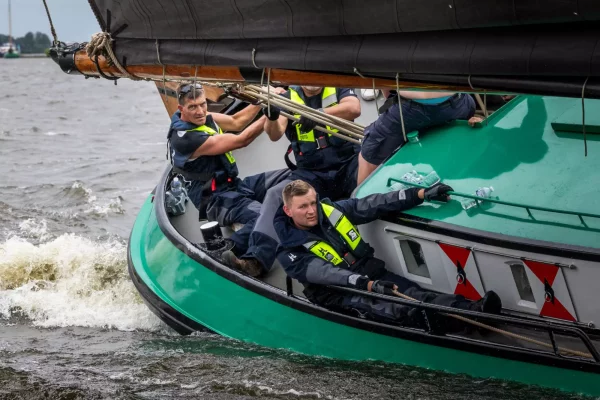 Bemanning van De Sneker Pan in zeilkleding aan boord van het skûtsje