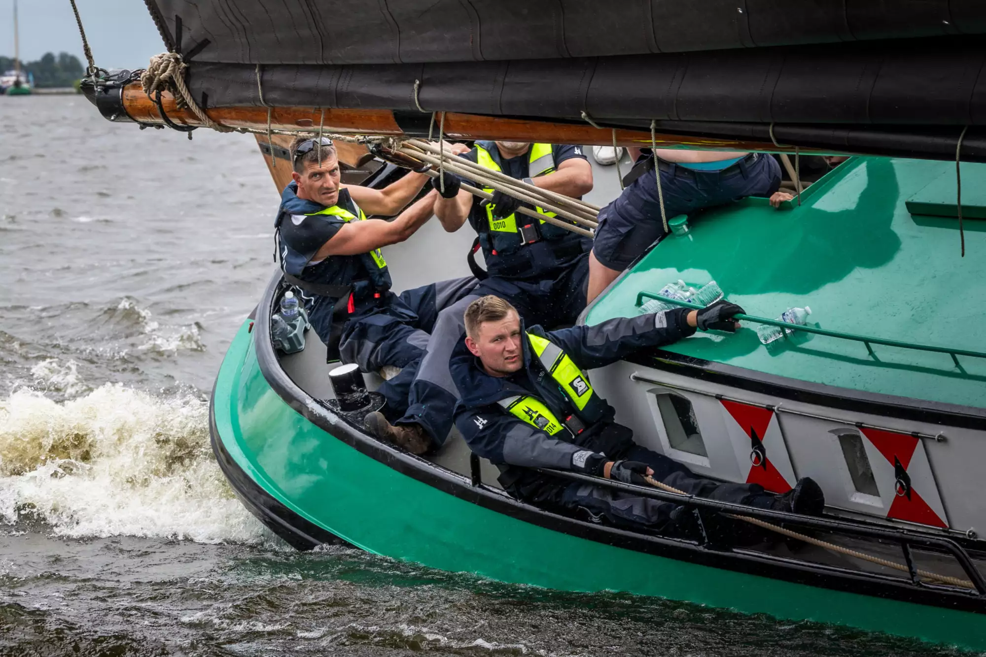 Bemanning van De Sneker Pan in zeilkleding aan boord van het skûtsje