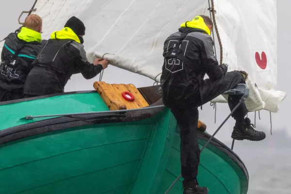Bemanning van De Sneker Pan in zeilkleding aan de reling