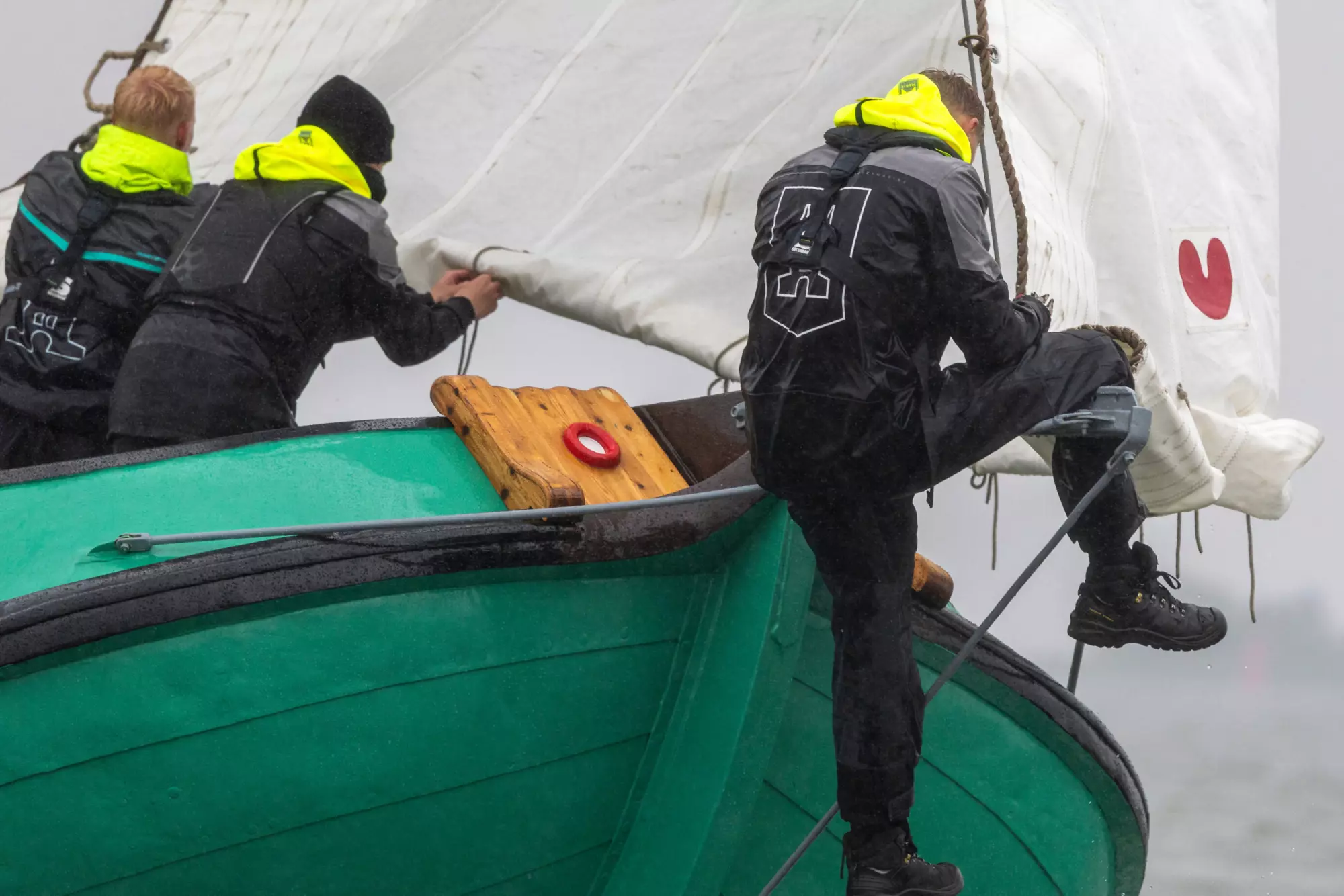 Bemanning van De Sneker Pan in zeilkleding aan de reling