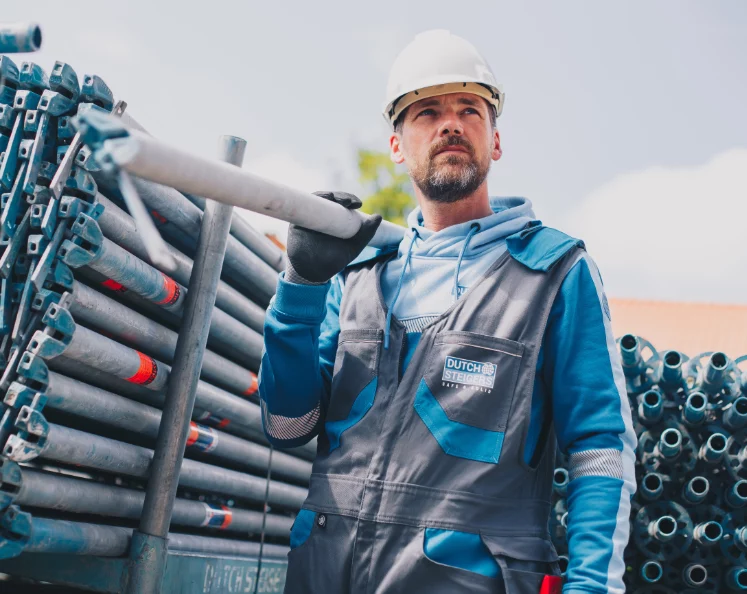 Medewerker in grijze werkkleding met helm tussen buizen