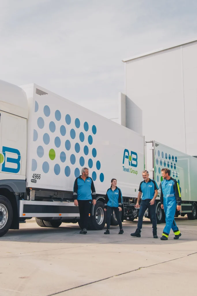 Chauffeurs van AB Texel in bedrijfskleding bij hun trucks