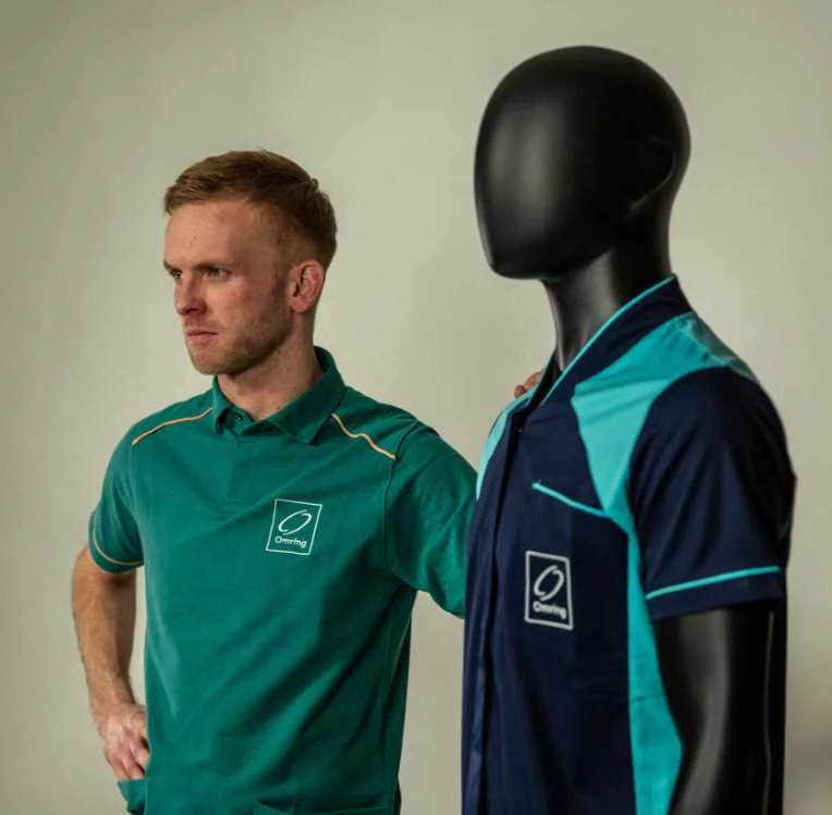 Zorgmedewerker in groene polo naast een paspop met zorgtuniek