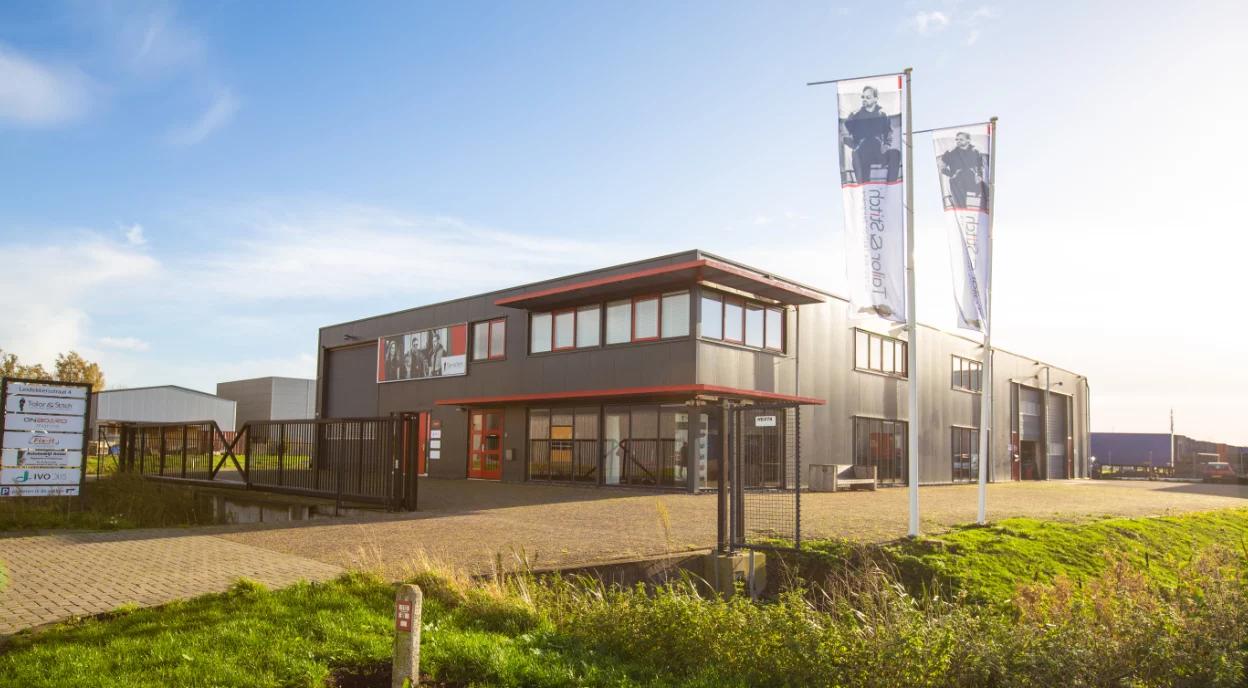 Bedrijfspand van Tailor & Stitch in Sneek met vlaggen