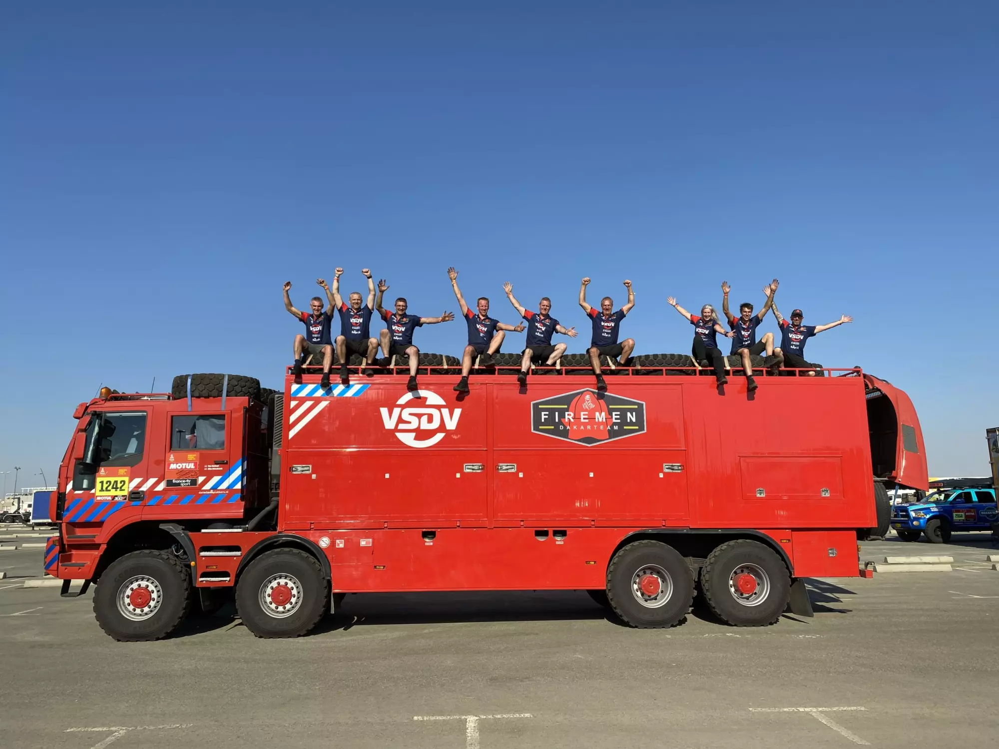 Team in bedrijfskleding op een rode rallytruck